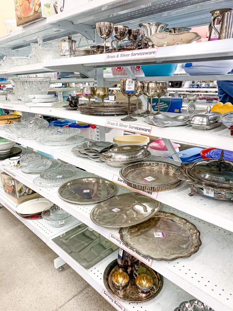 shelves in a thrift store displaying metal service ware items
