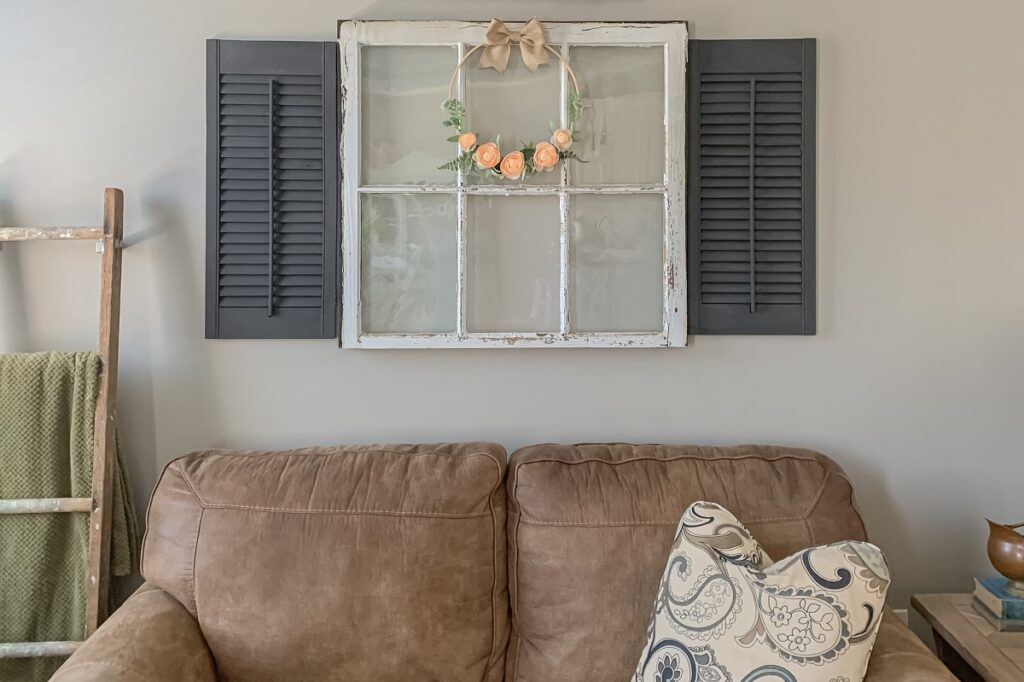 hoop wreath hanging on an old window above a couch