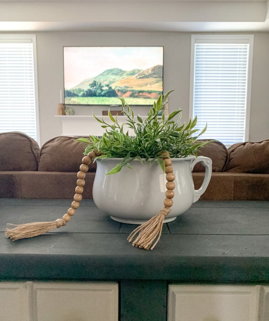antique ironstone chamber pot being used as a planter for decor on a sofa table